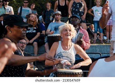 Montreal, Canada - June, 2018: African American and Caucasian women playing djembe drum bongo in tam tams or Mount Royal Park, Montreal, Canada.