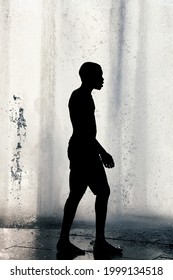 Montreal, Canada - June, 2018: Silhouette Of A Lonely African American Boy Walking In Front Of A Water Fountain.