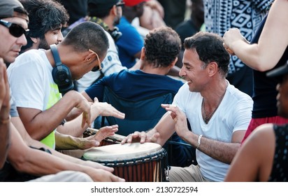 Montreal, Canada - June 2018: Two Canadian Caucasian man playing djembe drum bongo in the crowd in Mount Royal park tam tams festival.