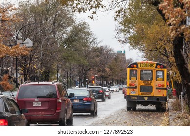 MONTREAL, CANADA - NOVEMBER 6, 2018: North American Yellow School Bus Parked On A Street, Waiting For Students With Cars Passing By With Information In French, According To Quebec French Speaking Rule