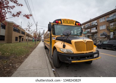 MONTREAL, CANADA - NOVEMBER 9, 2018: North American Yellow School Bus Parked On A Street, Waiting For Students With Cars Passing By With Information In French, According To Quebec French Speaking Rule