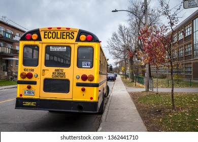 MONTREAL, CANADA - NOVEMBER 9, 2018: North American Yellow School Bus Parked On A Street, Waiting For Students With Cars Passing By With Information In French, According To Quebec French Speaking Rule