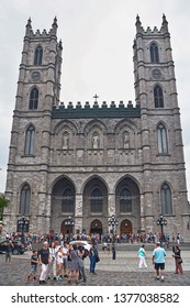 MONTREAL, CANADA - SEPTEMBER 3, 2018: The Place d'Armes street in front of the Notre-Dame Basilica in the Old Montreal, or vieux Montreal, tourists walk down the street. It is a landmark of Quebec