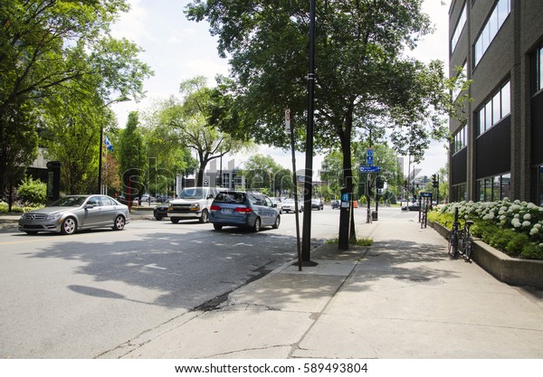 Montreal, Quebec, Canada - 18 July 2016 -\
Generic sunny green street in Montreal in summertime. Cars, bikes,\
trees and traffic signs as\
editorial