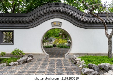 Montreal, Quebec, Canada -2022: Montreal Botanical Garden China area (Jardin botanique de Montréal, Jardin de Chine). A moon gate (yuèliàngmén) circular opening in a garden wall.
