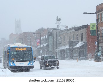 Montreal, Quebec, Canada - January 17 2022: A Bus And A Car Driving On The Urban Road During A Snowstorm In Traffic, Neighborhood Of Mile End. Bad Weather For Public Transit And Drivers Alike.