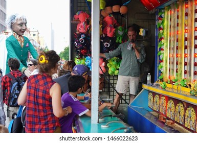 Montreal, Quebec / Canada - July 24, 2019: Excited Kids Play A Water Gun Carnival Game Umder The Owner's Watchful Eyes At Montreal Just For Laughs 2019