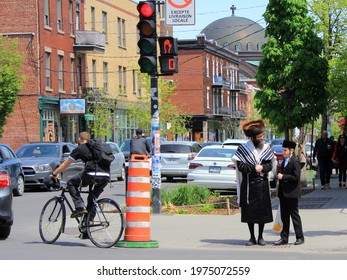 Montreal, Quebec Canada - May 15 2021: man in fur hat from the religious Hassidic Jews community in Mile End jewish neighborhood, in traditional clothes in the street, with a boy dressed in black.