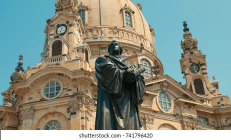 Monument of Martin Luther - the founder of the Reformation. The man holds a book in his hands and looks away, dressed in a gown.