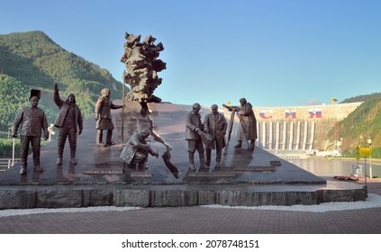 Monument On The River Bank Against The Backdrop Of The Dam Of The Largest Hydroelectric Power Station. Khakassia, Siberia, Russia