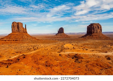 Monument Valley in daytime from top of the valley with dirt road in front - Powered by Shutterstock