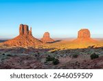 Monument Valley famous east west mittens and Merrick buttes at horizon colorful red sunset in Arizona, USA with orange canyon rock formations