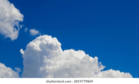 monumental cloud tower with a dense texture and picturesque sun-lit curves rises against the deep blueness of an open summer sky space during the daytime