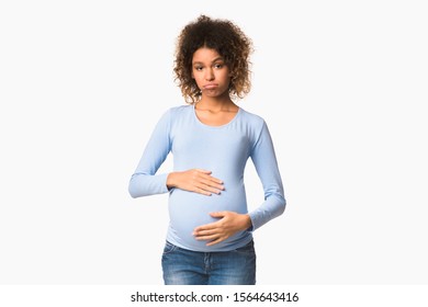 Mood Changes. Sad Black Pregnant Woman Posing To Camera Over White Background