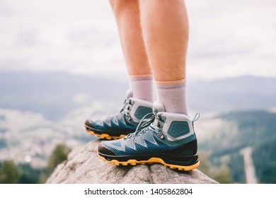 Mood Photo Of Male Legs Wearing Sportive Hiking Shoes With Strong Protective Sole. Mens Legs In Trekking Footwear For Mountain Travel Standing On Stone Outdoor At Nature On Abstract Background