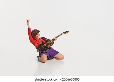 Mood, vibes. Stylish girl, retro musician wearing vintage style bright clothes playing guitar like rockstar isolated on white background. Vintage fashion, music, art, emotions, music festival concept.