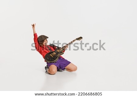 Mood, vibes. Stylish girl, retro musician wearing vintage style bright clothes playing guitar like rockstar isolated on white background. Vintage fashion, music, art, emotions, music festival concept.
