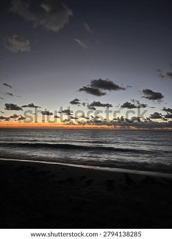 Moody dark beach at dusk with dramatic cloudy sky and ocean waves on shore