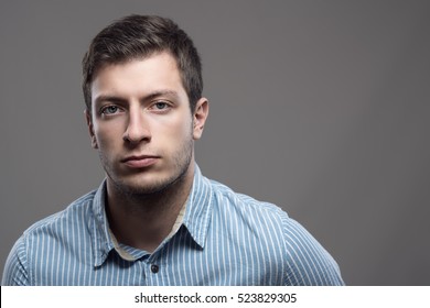 Moody dramatic portrait of serious young man in blue shirt looking at camera with copyspace  - Powered by Shutterstock