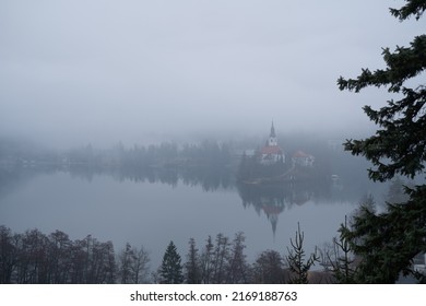 Moody Morning At Lake Bled With Thick Fog And Clouds, Still Water With Forest Frame, Slovenia