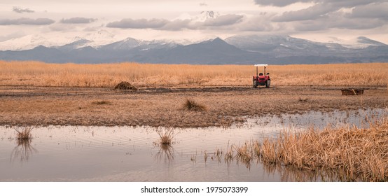 Moody panoramic view of a tractor in front of lake and marshes in Sultan Reedy (Sultansazligi) National Park, central Turkey with snow-capped mountains in the background - Powered by Shutterstock