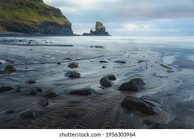 Moody seascape scenery and sea stack during sunrise or sunset at Talisker Bay Beach on the Isle of Skye, Scotland