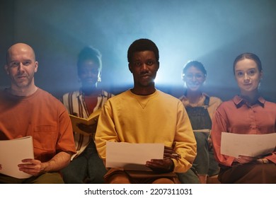 Moody Shot Of Black Young Man Backlit By Projector Rays Whle Sitting On Chair In Audience At Business Seminar