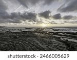 Moody sky with dramatic cloud formations over Carriagem Beach, Portugal. Rugged coastline and rock formations create a striking and atmospheric scene at dusk.