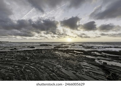 Moody sky with dramatic cloud formations over Carriagem Beach, Portugal. Rugged coastline and rock formations create a striking and atmospheric scene at dusk. - Powered by Shutterstock