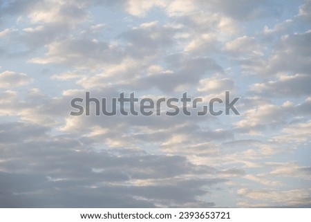 Moody sky with white and gray clouds against a pale blue sky, as a nature background
