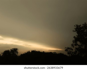Moody sunset with dramatic clouds and dark tree silhouettes. Perfect for wall art, background, or nature-themed digital projects.
