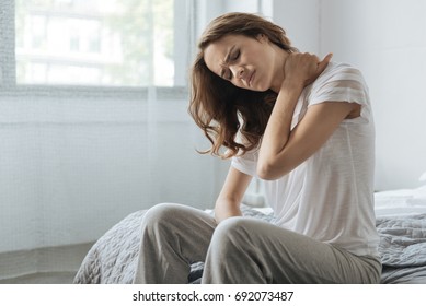 Moody young woman holding her neck - Shutterstock ID 692073487