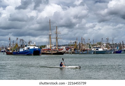 MOOLOOLABA, AUSTRALIA - Jan 22, 2022: A Lonely Kayaker Paddling In Front Of Fishing Trawler In Port Mooloolaba, Australia