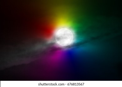 The moon appears in the night behind a cloud.
