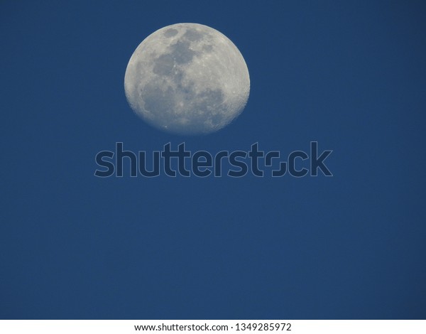 Moon in the blue\
sky.