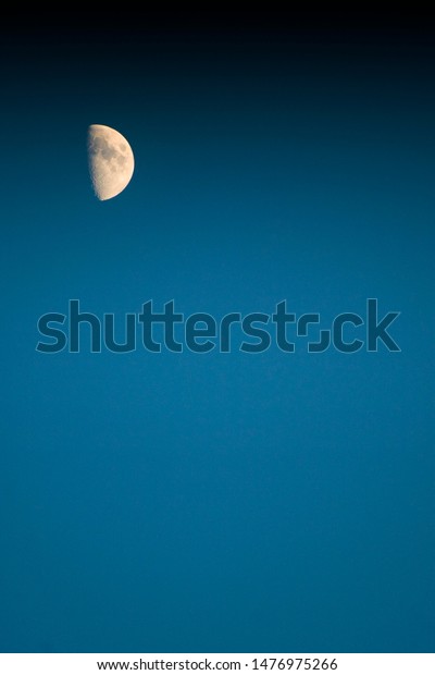 Moon in\
blue sky and black space. Vertical moon\
photo.