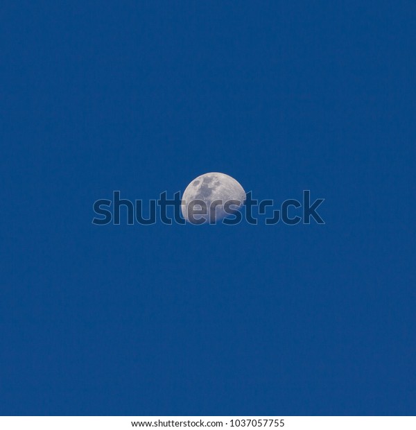 Moon in the blue sky at\
dusk.