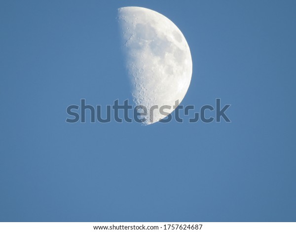 Moon in the blue\
sky. Large white moon on a clear blue sky without clouds in the\
daytime, sunny day time.
