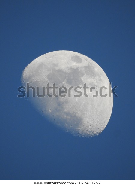 Moon in the daytime with\
blue sky