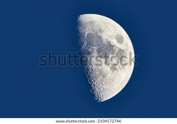 The Moon detailed\
shot in blue daylight sky, taken at 1600mm focal length, first\
quarter phase, dusk light