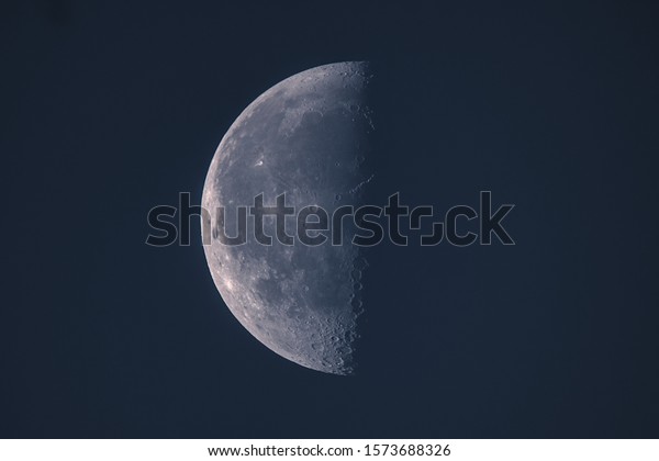 Moon in first quarter\
on dark blue sky