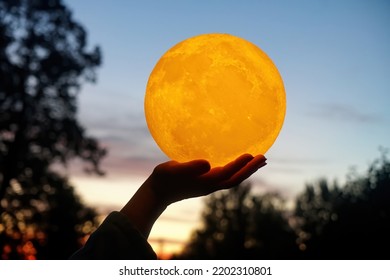  Moon In The Hand On Red Sunrise Background. Moon Bedside Lamp On The Sky                              