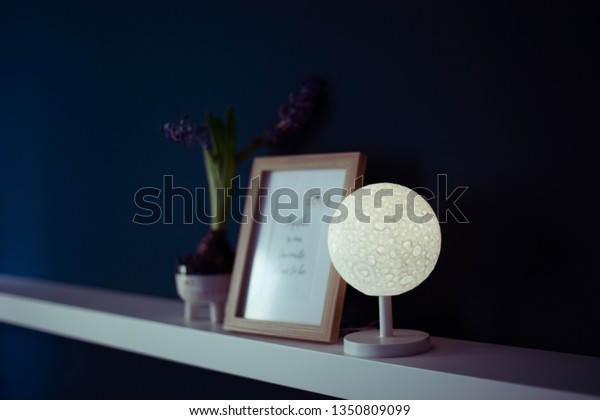 Moon lamp shade lit on\
bedroom shelf