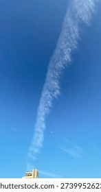 Moon and Linear Cloud Formation Over Urban Skyline.