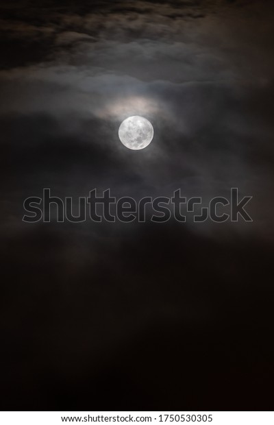 a
moon in the middle of darkness, surrounded by
clouds