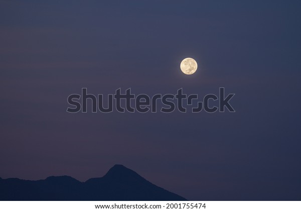 The moon and\
mountain silhouette in the sky, the night sky turns to morning in\
the tropical climate sky purple, blue, gray and black make a\
beautiful blend. Sentul,\
Indonesia.