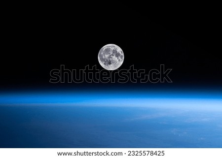 The moon orbits over the beautiful blue horizon and bend of the earth.