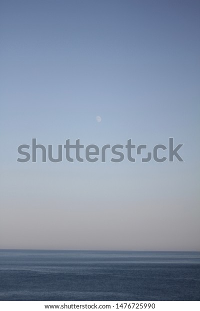 The moon over the sea.\
Blue evening