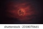 the moon in a red  sky with dark clouds