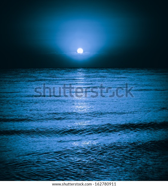 Moon reflecting in a lake sea ocean waves.\
Moonlight night background